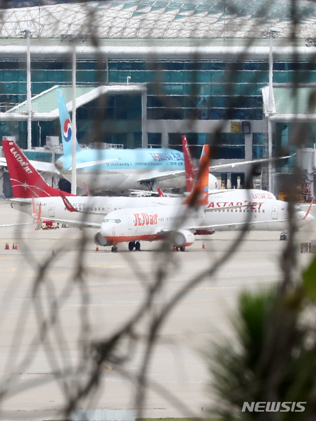 [인천공항=뉴시스] 이영환 기자 = 제주항공이 이스타항공에 통보한 인수합병(M&A) 선결 조건 이행 시한을 하루 앞둔 14일 오전 인천국제공항 여객터미널에 제주항공 비행기와 이스타항공 비행기가 멈춰 서 있다. 항공업계에 따르면 제주항공은 지난 1일 이스타항공에 "영업일 기준 10일 안에 미지급금 해소 등 선결조건을 이행하지 않을 시 계약을 파기할 수 있다"는 내용을 담은 공문을 보냈으며 이스타항공이 15일까지 250억원가량의 체불임금을 포함한 1700억원대의 미지급금을 갚아야 한다는 의미다. 2020.07.14. 20hwan@newsis.com