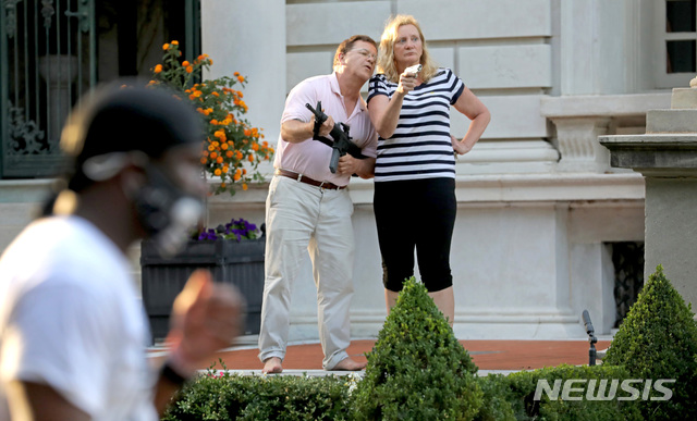 [세인트루이스=AP/뉴시스] 미국 미주리주 세인트루이스에서 '흑인 목숨도 소중하다' 시위대를 향해 총기를 겨누며 위협했던 백인 부부가 24일(현지시간) 공화당 전당대회에서 화상으로 도널드 트럼프 대통령 지지 선언을 할 예정이다. 사진은 지난 6월28일 세인트루이스에 있는 자신의 집 앞에서 사유지를 침범했다는 이유로 총을 들고 시위대를 위협하는 마크 맥클로스키와 부인 퍼트리샤의 모습. 2020.08.18 