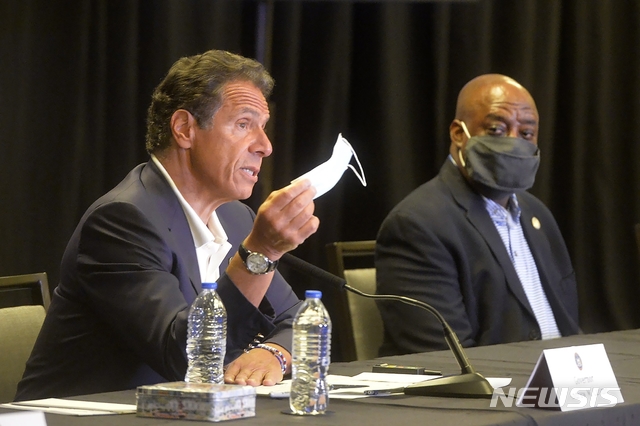 사바나( 미 조지아주)= AP/뉴시스] 앤드루 쿠오모 뉴욕주지사는 20일(현지시간) 조지아주 사바나시로 날아가 하이야트호텔에서 열린 기자회견에서 마스크를 들어보이며 방역대책을 설명했다. 밴 존슨시장(오른쪽)이 옆에서 경청하고 있다.&nbsp; 