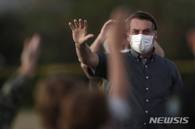 [브라질리아=AP/뉴시스]자이르 보우소나루 브라질 대통령이 20일(현지시간) 브라질리아의 대통령관저 밖에서 마스크를 쓴 채 지지자들에게 손을 흔들고 있는 모습. 그는 지난 7일 신종 코로나바이러스 감염증(코로나19) 확진 판정을 받았다. 2020.7.22. 