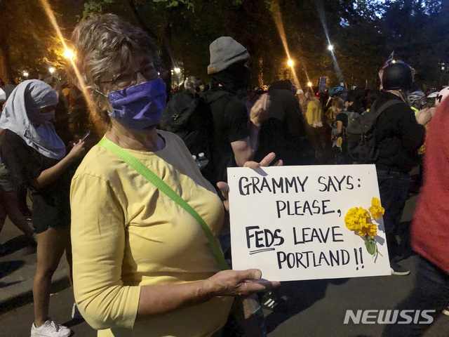 [포틀랜드=AP/뉴시스]미국 오리건 주 포틀랜드의 연방법원 앞에서 79세 할머니 마디 위드먼이 20일(현지시간) "할머니가 말하는데, 연방요원들은 제발 포틀랜드를 떠나라"라고 쓴 손 팻말을 들어보이며 시위를 벌이고 있다. 위드먼은 흑인 남성 조지 플로이드 사망사건 이후 시위에 나서기는 이번이 처음이라며, 질서회복을 빌미로 포틀랜드에 연방요원들을 투입한 도널드 트럼프 정부의 결정 때문에 분노해 거리로 나서게 됐다고 밝혔다. 2020.07.22