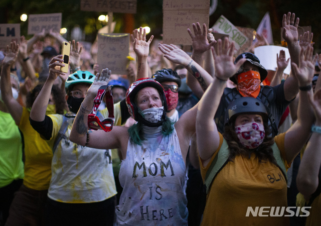 [포틀랜드=AP/뉴시스] 미국 오리건주 포틀랜드에서 20일(현지시간) 중년 여성들이 '흑인의 생명도 소중하다' 시위에 참여하고 있다. 이날 시위 현장에서 일명 '엄마의 벽'을 만든 이들은 포틀랜드에 연방요원들을 투입한 트럼프 정부를 강하게 비난했다. 가운데 여성의 흰색 셔츠에 "엄마 여기있다"라고 씌여있다. 2020. 07.22 