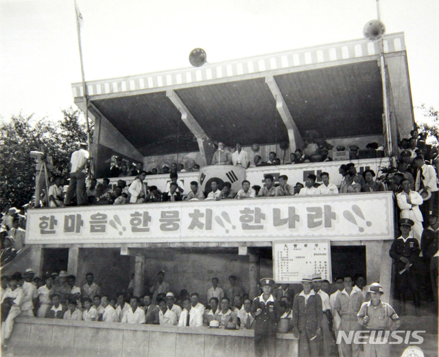 [서울=뉴시스] 1948년 8월 15일 부산 구덕운동장에서 개최된 독립기념 행사장 모습. 단상에 걸린 ‘한마음, 한뭉치, 한나라’라는 구호에는 남과 북이 다시 하나 되기를 바라는 간절한 소망이 담겨 있었지만 1949년부터 38선상에서 남북의 충돌은 빈발해졌다. (사진=미국 국립문서기록청) 2020.07.26. photo@newsis.com (* 위 사진은 재배포, 재판매, DB 및 활용을 금지합니다)