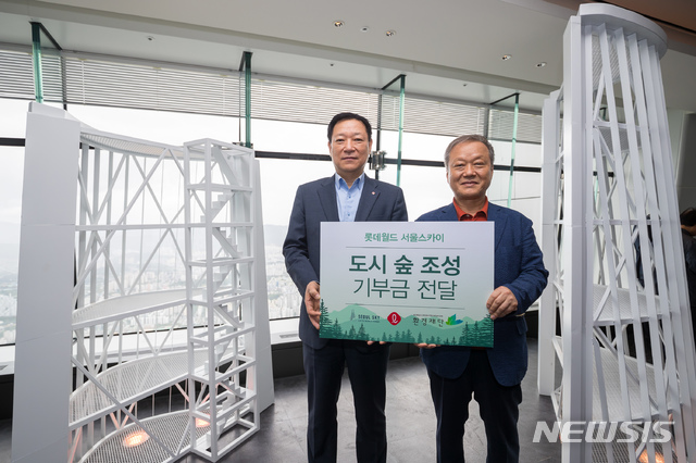 [서울=뉴시스]24일 롯데월드타워 서울스카이에서 열린 기부금 전달식에서 기념촬영하는 롯데월드 최홍훈 대표와 환경재단 최열 이사장