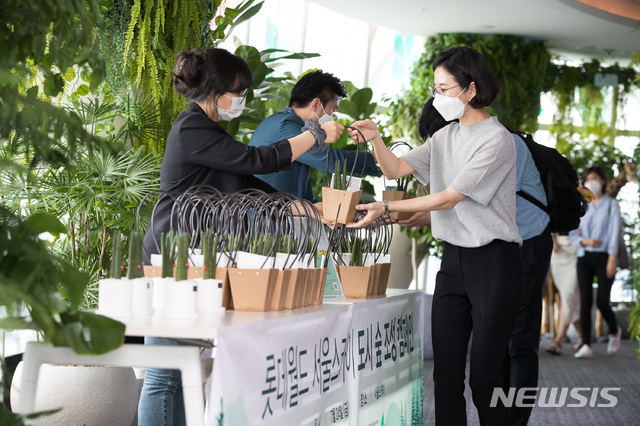 [서울=뉴시스]24일 롯데월드타워 서울스카이를 찾은 관람객에게 스투키 화분을 선물하는 모습