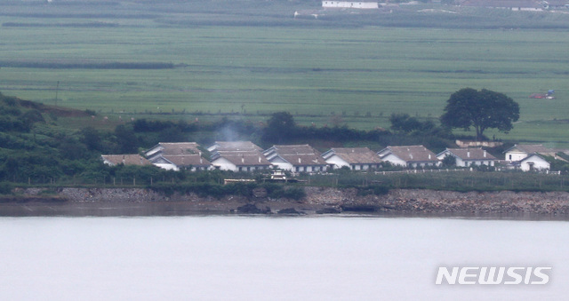 [서울=뉴시스] 전진환 기자 = 월북한 것으로 추정된 20대 탈북민이 최근 경기 김포지역에서 성폭행 혐의로 경찰 조사를 받고 구속영장이 발부된 것으로 확인됐다. 합동참모본부는 27일 '해당 인원이 월북했을 추정 위치를 강화도 일대에서 특정했다' 이어 '해당 인원을 특정할 수 있는 유기된 가방을 발견하고 현재 정밀조사중'이라고 밝혔다. 사진은 27일 강화도에서 바라본 개풍군의 한 마을에서 연기가 피어오르고 있다. 2020.07.27.&nbsp; amin2@newsis.com 