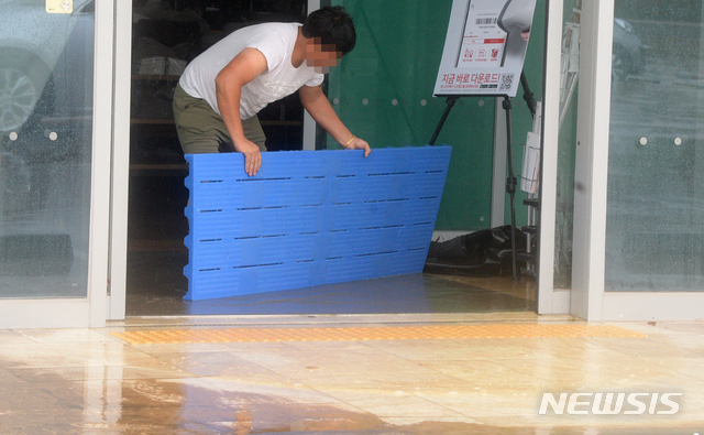 [전주=뉴시스] 김얼 기자 = 지속적인 장마가 이어지며 전북지역에 호우경보가 내린 지난 30일 전북 전주시 완산구 효자동의 한 의류매장이 빗물에 잠기자 매장 관계자가 가게에서 물을 빼내고 있다. 2020.07.30.pmkeul@newsis.com