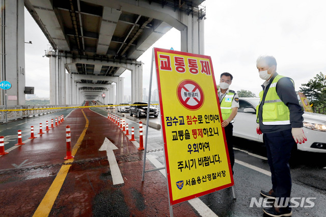 [서울=뉴시스]김병문 기자 = 중부지방에 집중호우가 내리는 2일 오후 서울 용산구 잠수교에서 교통경찰이 보행자와 자전거 통행을 제한하는 안내판을 설치하고 있다. 2020.08.02.&nbsp; dadazon@newsis.com