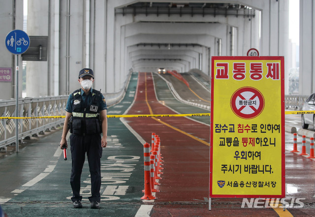 [서울=뉴시스]김병문 기자 = 중부지방에 집중호우가 내리는 2일 오후 서울 용산구 잠수교에서 교통경찰이 보행자와 자전거 통행을 제한하고 있다. 2020.08.02. dadazon@newsis.com