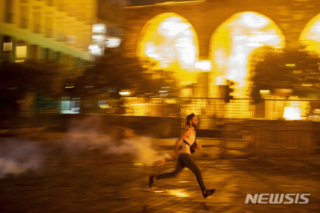 [베이루트=AP/뉴시스]7일(현지시간) 레바논 베이루트에서 한 반정부 시위자가 수십 년간 나라를 통치해온 정치인들에 대한 시위 도중 전경들에게 최루탄을 되던지고 있다. 2020.08.07.&nbsp; 