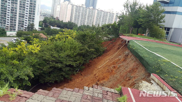 [부산=뉴시스] 9일 오전 11시 30분께 부산 남구 대한상공회의소 부산인력개발원 운동장 가장자리에서 높이 10m, 폭 40m 크기로 붕괴됐다. (사진=부산경찰청 제공)