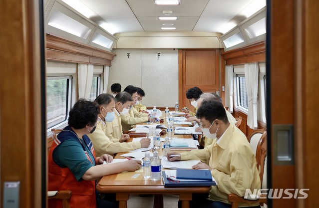 [서울=뉴시스]문재인 대통령이 12일 오전 집중호우 피해지역으로 향하는 전용열차 내 회의실에서 산림청, 농림부, 재난안전관리본부, 대한적십자사 등 관계부처 및 민관지원기관 관계자들로부터 집중호우 피해지역 상황을 보고 받고 있다. (사진=청와대 제공) 2020.08.12. photo@newsis.com