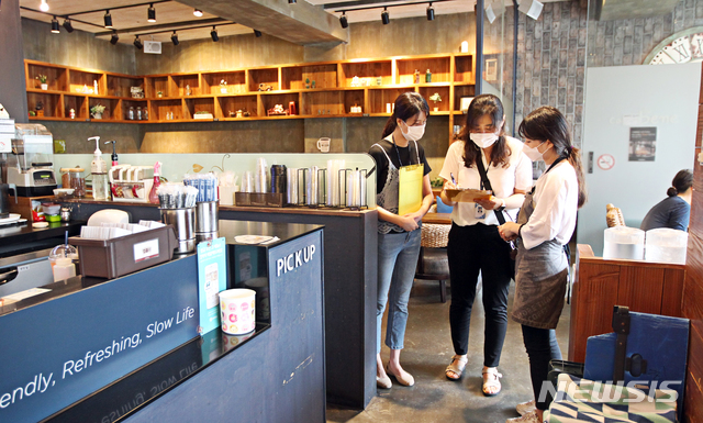 [서울=뉴시스]동작구청 관계자가 13일 서울 대방동에 위치한 커피전문점에서 신종 코로나바이러스 감염증(코로나19) 지역사회 확산 차단을 위해 탁자 간 거리 유지하기를 업소종사자에게 안내하고 있다. (사진=동작구 제공) 2020.08.13. photo@newsis.com