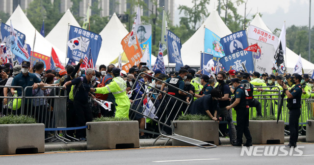 [서울=뉴시스]추상철 기자 =보수단체 집회 참가자들이 15일 오전 서울 종로구 광화문광장에서 8·15 국민대회 집회중 경찰이 세워놓은 바리게이트를 넘고 있다. 2020.08.15.&nbsp; scchoo@newsis.com