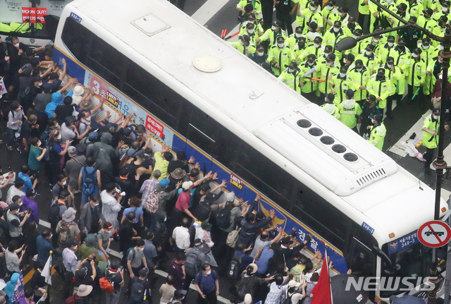 [서울=뉴시스]김명원 기자 = 지난 8월15일 서울 종로구 광화문 광장에서 열린 보수성향 단체 집회 참가자들이 경찰 버스를 밀고 있다. 2020.08.15. kmx1105@newsis.com