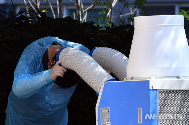 [부산=뉴시스] 하경민 기자 = 최근 부산지역에 신종 코로나바이러스 감염증(코로나19) 확진자가 잇달아 나오고 있는 가운데 20일 오전 연제구 보건소 선별진료소에서 한 직원이 이동식 냉풍기로 더위를 식히고 있다. 2020.08.20. yulnetphoto@newsis.com