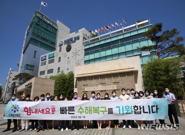 크레텍 직원들이 본사앞에서 수해의 빠른 극복을 기원하는 플래카드를 내 보이며, 응원하고 있다.  