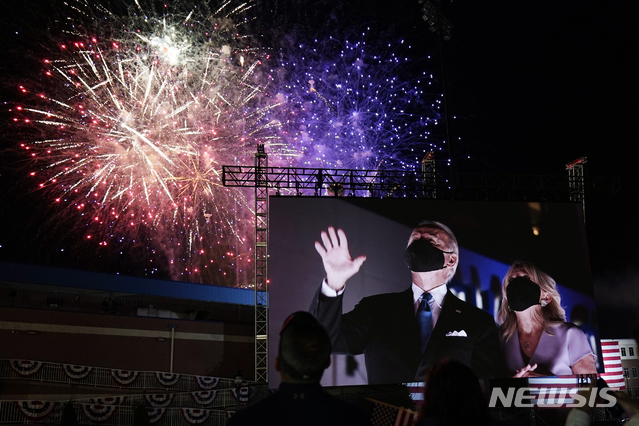 [ 윌밍턴=AP/뉴시스]조 바이든 미국 민주당 대통령 후보(왼쪽)와 질 바이든 여사가 20일(현지시간) 델라웨어주 윌밍턴 체이스 센터 밖에 마련된 무대 위에 올라 화려한 불꽃놀이를 바라보며 손을 흔드는 모습이 대형화면에 비춰지고 있다.  2020.08.21