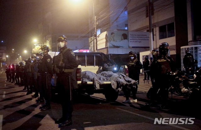 [리마=AP/뉴시스]23일(현지시간) 페루 경찰이 리마의 한 나이트클럽에서 숨진 시신 2구 주변에 서서 대응하고 있다. 앞선 22일 밤 나이트클럽에 모여 놀던 사람들이 경찰 급습 소식에 서로 먼저 빠져나가려다 압사하는 등 13명이 사망했다. 페루는 코로나19 확산 방지를 위해 지난 3월부터 술집, 나이트클럽을 폐쇄했으며 최근에는 직계 가족이 아닌 확대 가족 간의 만남도 못 하게 하고 야간 통금을 실시하고 있다. 2020.08.24.