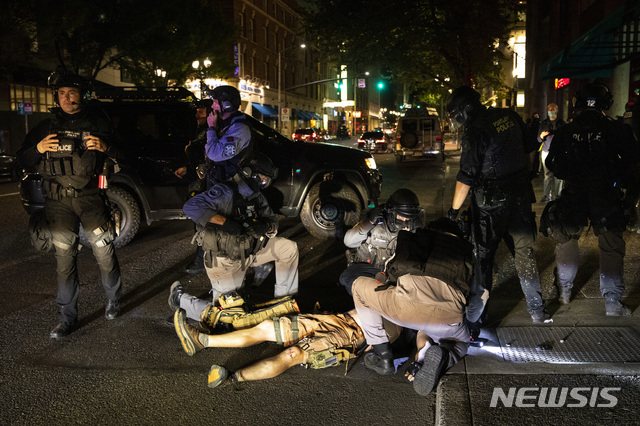 [포틀랜드=AP/뉴시스]미국 오리건주 포틀랜드에서 29일(현지시간) 경찰들이 총에 맞아 쓰러진 남성에 응급조치를 하고 있다. 이 남성은 결국 숨졌다. 이번 사건은 포틀랜드 시내에서 인종차별 항의시위대와 도널드 트럼프 지지자들이 충돌한 가운데 벌어졌다. 2020.08.30