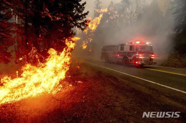 [프레스노( 미 캘리포니아주)= AP/뉴시스] 여러 곳의 산불이 동시다발로 확산되면서 7일(현지시간) 프레스노 지역에서는 산불진화를 위해 달려가는 소방트럭보다 더 빨리 도로변 산불이 번져가고 있다. 
