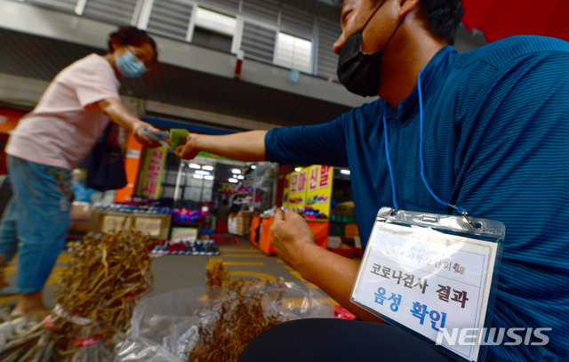 [광주=뉴시스] 류형근 기자 = 14일 오전 광주 북구 말바우시장 한 가게의 상인이 '신종 코로나바이러스 감염증(코로나19) 음성'의 내용이 적힌 '목걸이 안내문'이 걸고 장사를 하고 있다. 이 시장은 최근 한 식당에서 코로나19 확진자가 발생해 이틀간 폐쇄됐다. 2020.09.14. hgryu77@newsis.com