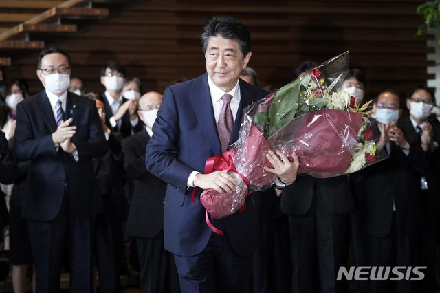 [도쿄=AP/뉴시스]아베 신조 일본 총리가 16일 도쿄 총리공관을 떠나기 전 꽃다발을 받고 인사하고 있다. 아베 총리와 내각은 이날 오전 임시 각의를 열고 총사퇴했으며 아베 정권의 계승을 표방하는 스가 요시히데) 총리 내각이 공식 출범한다. 2020.09.16.