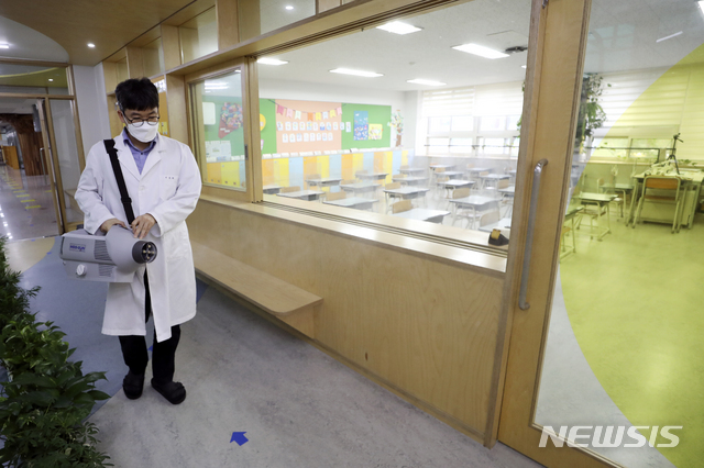 [서울=뉴시스] 최진석 기자 = 오는 21일부터 서울·경기·인천 수도권의 유치원과 초등학교, 중학교, 고등학교가 등교를 재개한다. 전면 원격수업이 종료되고 전교생의 3분의 1 이하로 등교할 수 있다. 3학년을 중심으로 등교하던 고등학교도 전교생 3분의 2 이하로 제한이 완화된다. 사진은 17일 서울 노원구 화랑초등학교 1학년 교실에서 학교 관계자가 방역 작업을 하는 뒤로 학생들의 원격수업이 진행되고 있는 모습. 2020.09.17.myjs@newsis.com