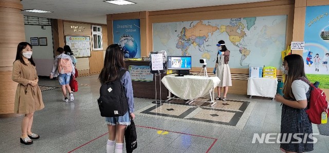 [수원=뉴시스]천의현 기자=21일 경기 수원 원일초 학생들이 중앙현관에 설치된 열화상 카메라에서 체온 측정을 하고 있다.
