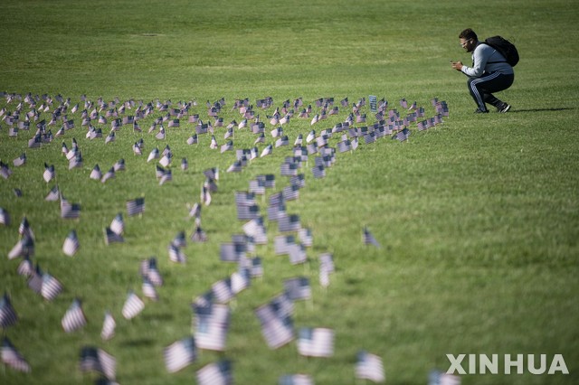 [워싱턴=신화/뉴시스]22일(현지시간) 미국 워싱턴 DC의 내셔널 몰에서 한 남성이 하는 코로나19로 사망한 희생자 20만 명을 상징하는 미국 국기를 사진으로 찍고 있다. 미 존스홉킨스대 시스템과학공학센터(CSE)는 미국의 코로나19 누적 확진자 수는 709만7937명, 사망자는 20만5471명이라고 발표했다. 2020.09.23.