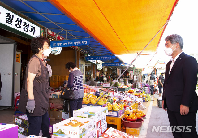 [서울=뉴시스]윤종원 IBK기업은행장(오른쪽)이 28일 IBK희망디자인 사업으로 새롭게 탈바꿈한 전남 구례 5일시장에서 과일을 구입하기 전 상인과 이야기를 나누고 있다. 2020.9.28 (사진=IBK기업은행 제공) photo@newsis.com