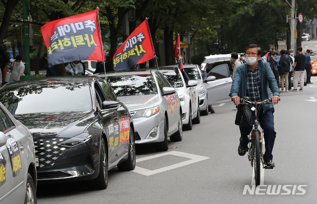 [서울=뉴시스] 박진희 기자 = 3일 오후 서울 강동구민회관 인근에서 진행된 보수단체 새로운한국을위한국민운동(새한국) 주최 개천절 차량집회에 참여한 차량 옆으로 한 시민이 자전거를 타고 지나가고 있다. 2020.10.03.pak7130@newsis.com