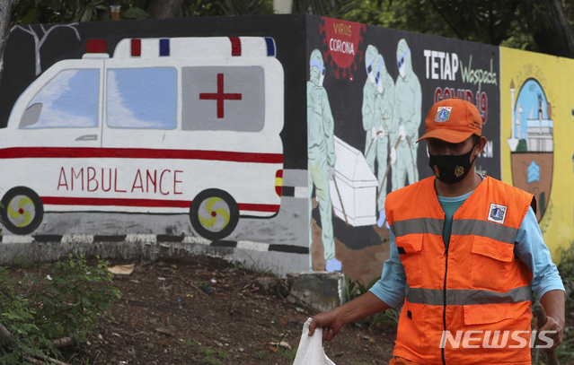 [자카르타=AP/뉴시스] 10월5일 인도네시아 자카르타에서 마스크를 쓴 한 청소근로자가 코로나19 확산 예방 벽화 앞을 지나고 있다. 인도네시아의 코로나19 누적 확진자 수는 30만3498명, 사망자는 1만1151명으로 집계됐다. 2020.10.05.