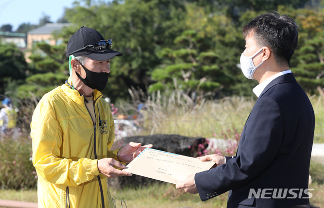 [서울=뉴시스] 조수정 기자 = 북한 피격으로 사망한 공무원 A씨 형 이래진 씨가 8일 서울 청와대 분수대 앞에서 고영호 청와대 시민사회수석 비서관실 행정관과 만나 A씨의 아들이 작성한 원본 편지를 전달하고 있다. 2020.10.08.&nbsp; chocrystal@newsis.com