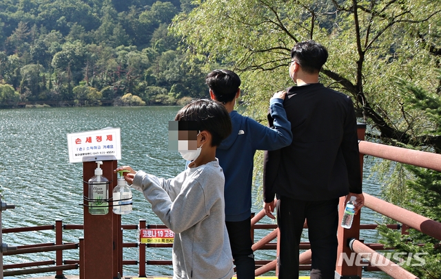[증평=뉴시스]강신욱 기자 = 주말인 10일 충북 증평군 증평읍 율리 삼기저수지 등잔길 데크로드에 가을 정취를 느끼려는 사람들의 발길이 이어진 가운데 한 어린이가 입구에 있는 소독제로 손을 소독하고 있다. 2020.10.10. ksw64@newsis.com