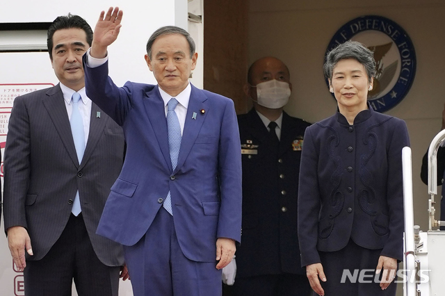 [하네다=AP/뉴시스]스가 요시히데 총리(가운데)가 마리코 여사(가장 오른쪽)와 베트남으로 출국하기 전 하네다 공항에서 손을 흔들고 있다. 2020.10.19.