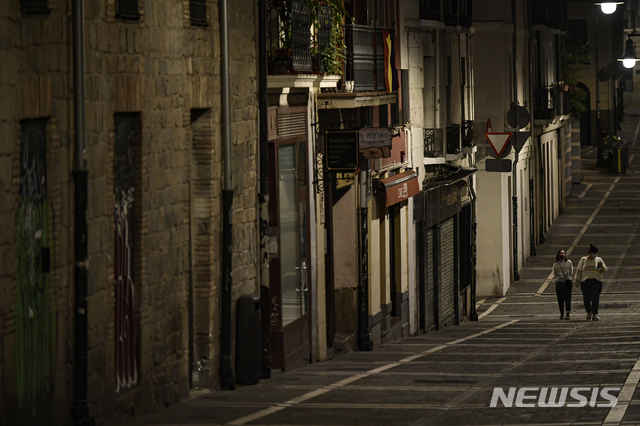 [팜플로나(스페인)=AP/뉴시스]24일(현지시간) 스페인 북부 팜플로나의 텅 빈 거리를 마스크를 쓴 주민 2명이 걷고 있다. 페드로 산체스 스페인 총리는 25일 스페인 전역에 2차 국가비상사태를 선포하고 신종 코로나바이러스 감염증(코로나19)의 재창궐을 막기 위해 야간 통행금지를 명령했다고 밝혔다. 2020.10.25