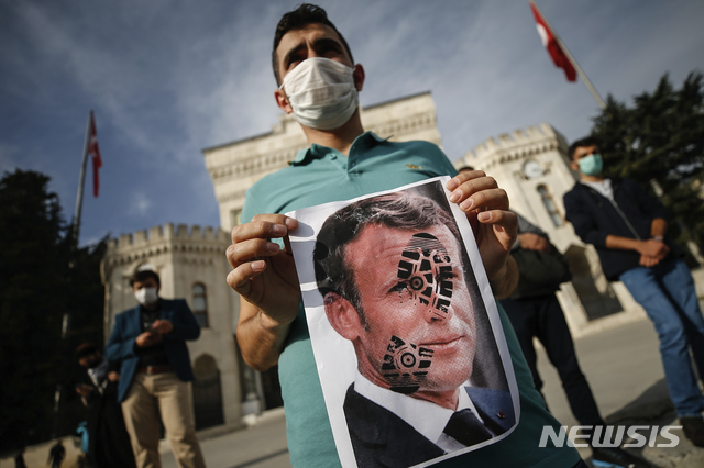 [이스탄불=AP/뉴시스]25일(현지시간) 터키 이스탄불에서 한 남성이 프랑스에 대한 시위 도중 신발 자국이 찍힌 에마뉘엘 마크롱 프랑스 대통령의 사진을 들고 있다. 레제프 타이이프 에르도안 터키 대통령은 마크롱 대통령에 대해 연이틀 "정신과 검사를 받을 필요가 있다"라며 비난했다. 앞서 프랑스는 에르도안의 정신 감정이 필요하다는 말에 항의의 표시로 터키 주재 자국 대사를 소환했다. 2020.10.26.