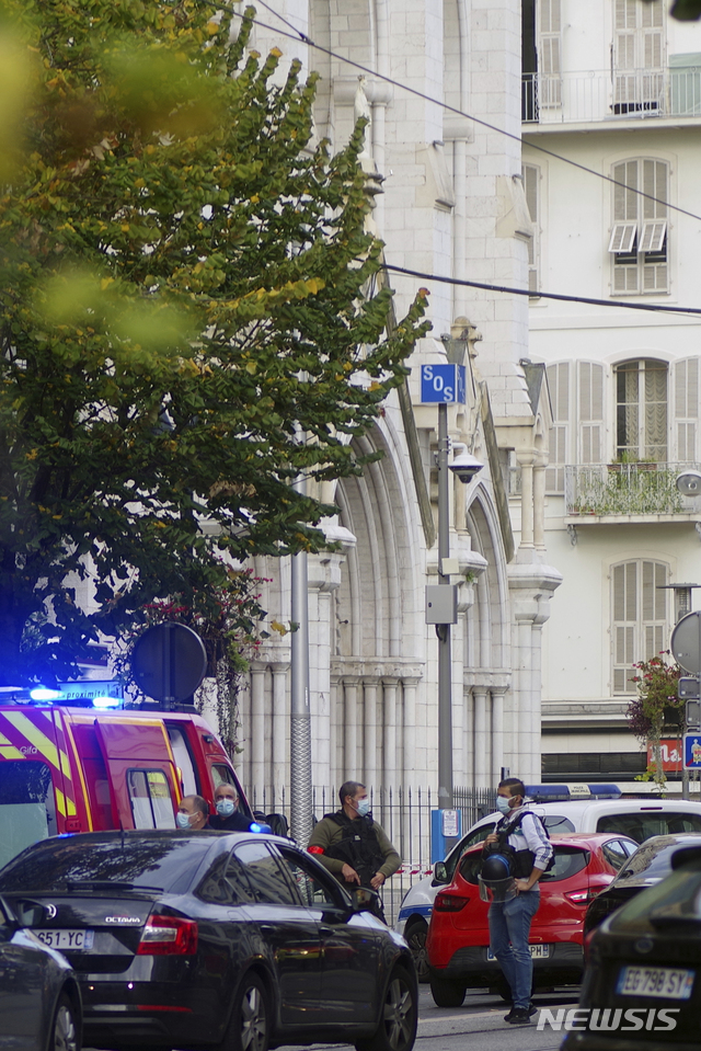 French policemen stand next to Notre Dame church after a knife attack, in Nice, France, Thursday, Oct. 29, 2020. French anti-terrorism prosecutors are investigating a knife attack at a church in the Mediterranean city of Nice that killed two people and injured several others. (AP Photo/Alexis Gilli)