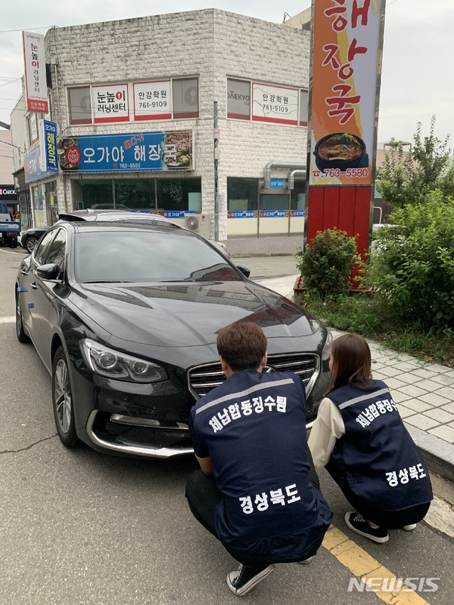 [안동=뉴시스] 차 번호판을 떼내고 있는 단속 직원들. (사진=경북도 제공) 2021.11.22