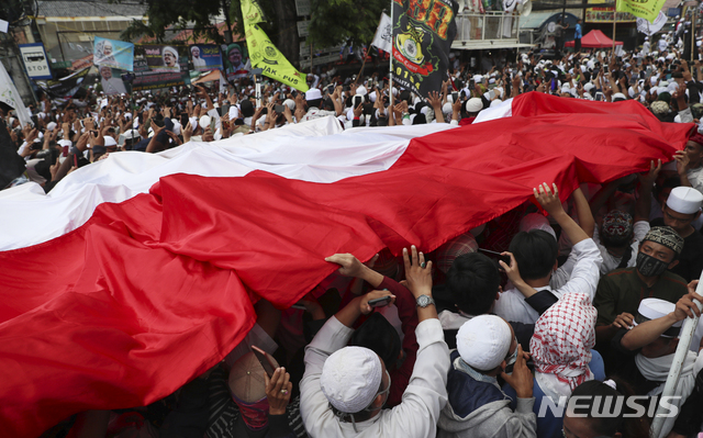 [자카르타=AP/뉴시스] 10일 사우디로 망명간 선동적 이슬람 성직자로 이슬람주의 보호전선 지도자 라지에크가 3년만에 귀국하자 추종 무슬림들이 인니 국기를 들고 환영 시위를 하고 있다. 이 성직자에 대한 포르노 혐의도 귀국과 함께 취소되었다. 