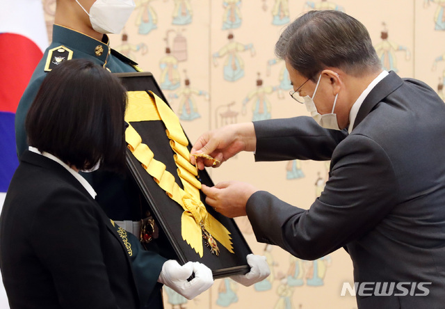 [서울=뉴시스]박영태 기자 = 문재인 대통령이 12일 청와대 본관에서 열린 전태일 열사 훈장 추서식에 참석해 전태일 열사의 둘째동생 전순옥 씨 옆의 의장병이 들고 있는 추서판에 부장을 걸어주고 있다. 2020.11.12. since1999@newsis.com