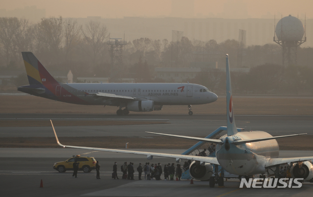 [서울=뉴시스] 조수정 기자 = 대한항공이 아시아나항공을 인수하기로 한 16일 서울 강서구 김포국제공항 국내선청사 전망대에서 바라본 계류장에 대한항공 여객기 너머로 아시아나항공 여객기가 착륙하고 있다. 2020.11.16. chocrystal@newsis.com