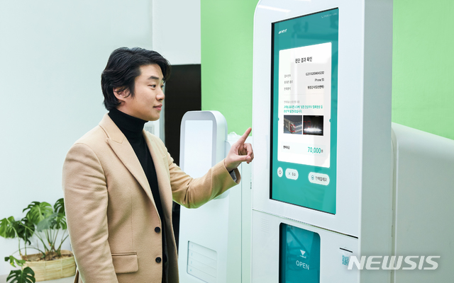 [서울=뉴시스]민팃ATM 모델인 안재홍이 휴대폰 검사결과 기능을 이용하고 있다.