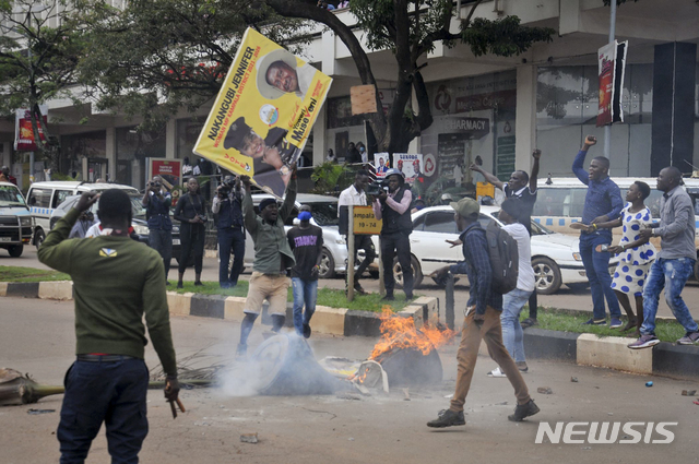 [캄팔라=AP/뉴시스]18일(현지시간) 우간다 수도 캄팔라에서 야당 대통령 후보 보비 와인(본명 로버트 캬굴라니)을 지지하는 시위대가 요웨리 무세베니 현 대통령의 사진이 담긴 현수막을 불에 태우려 하고 있다. 우간다 경찰은 내년 대선에서 대통령을 노리는 음악가 겸 야당 지도자 보비 와인이 경찰에 체포된&nbsp; 후 시위가 벌어져 3명이 숨지고 38명이 다쳤다고 밝혔다. 2020.11.19.