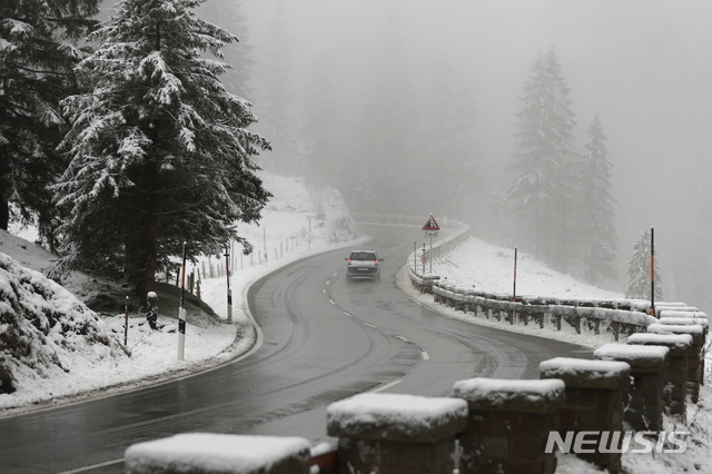 [스피칭제=AP/뉴시스] 20일 독일 남부 바이에른주 호수지역에서 눈이 내린 길을 차가 달리고 있다 