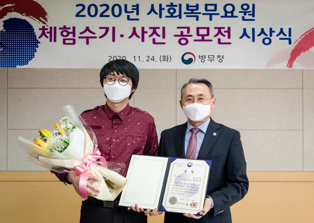 [서울=뉴시스] 모종화 병무청장이 24일 정부대전청사에서 열린 2020년 사회복무요원 체험수기·사진 공모전 시상식에서 수기 부문 최우수상(제목 : “우리는 작은 영웅입니다”)을 받은 박영상 요원(대구의료원 복무)과 기념촬영하고 있다. 2020.11.24. (사진=병무청 제공)