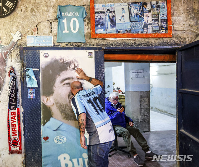 [나폴리=AP/뉴시스]25일(현지시간) 이탈리아 나폴리에서 디에고 마라도나의 유니폼을 입은 한 축구 팬이 마라도나 포스터에 입 맞추고 있다. 1986년 아르헨티나를 월드컵 우승으로 이끈 아르헨티나 축구 영웅 디에고 마라도나가 25일 아르헨티나 부에노스아이레스 자택에서 심장마비로 타계했다. 향년 60세. 2020.11.26.&nbsp; 