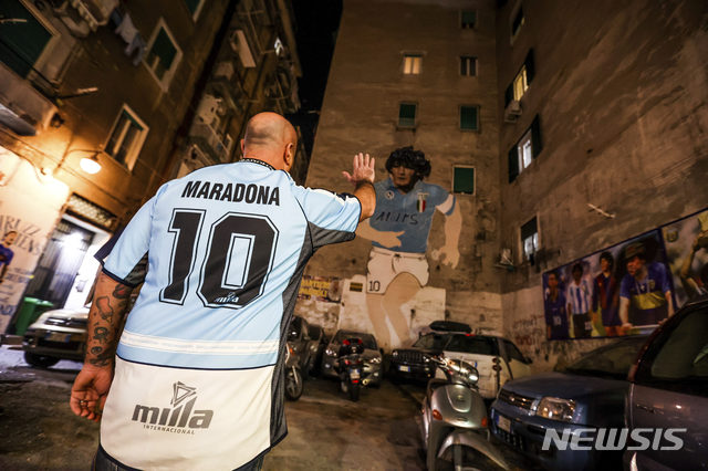  [나폴리=AP/뉴시스]25일(현지시간) 이탈리아 나폴리에 있는 축구 전설 디에고 마라도나의 벽화 앞에서 그의 유니폼을 입은 한 남성이 손을 흔들며 작별 인사를 하고 있다. 1986년 아르헨티나를 월드컵 우승으로 이끈 아르헨티나 축구 영웅 디에고 마라도나가 25일 아르헨티나 부에노스아이레스 자택에서 심장마비로 타계했다. 향년 60세. 2020.11.26. 