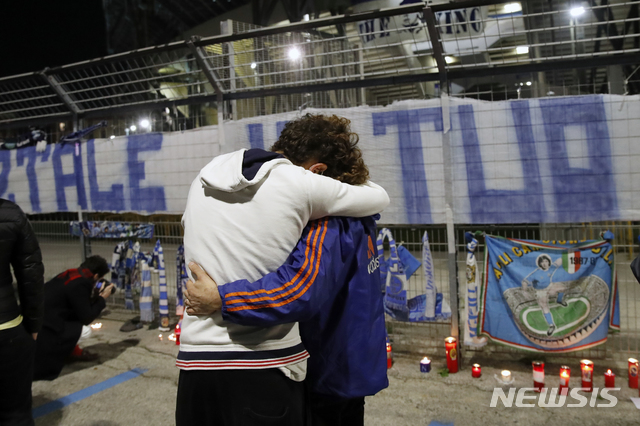 [나폴리=AP/뉴시스]25일(현지시간) 이탈리아 나폴리의 산 파올로 경기장 밖에서 축구 팬들이 서로 부둥켜 안으며 디에고 마라도나의 죽음을 애도하고 있다. 1986년 아르헨티나를 월드컵 우승으로 이끈 아르헨티나 축구 영웅 디에고 마라도나가 25일 아르헨티나 부에노스아이레스 자택에서 심장마비로 타계했다. 향년 60세. 2020.11.26. 